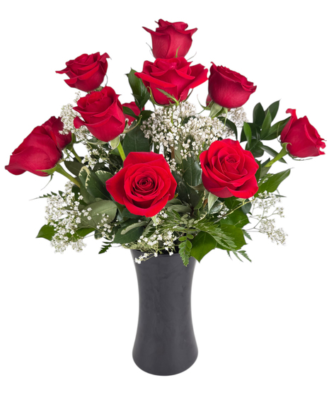 One dozen red roses and greenery in a clear glass vase.